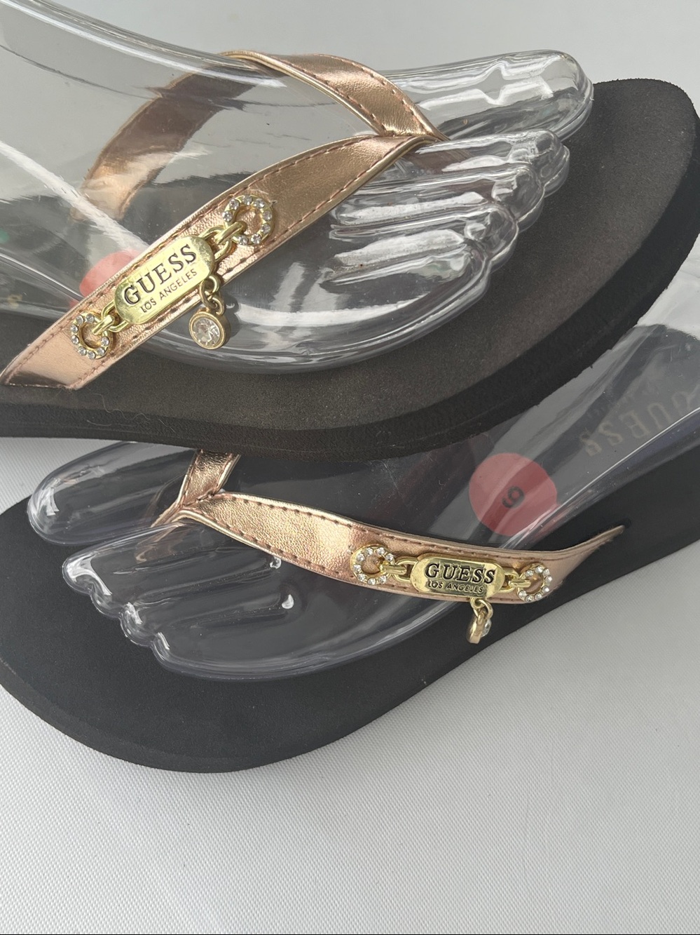 GUESS flip-flop featuring rose metallic gold straps & branded diamond charms New